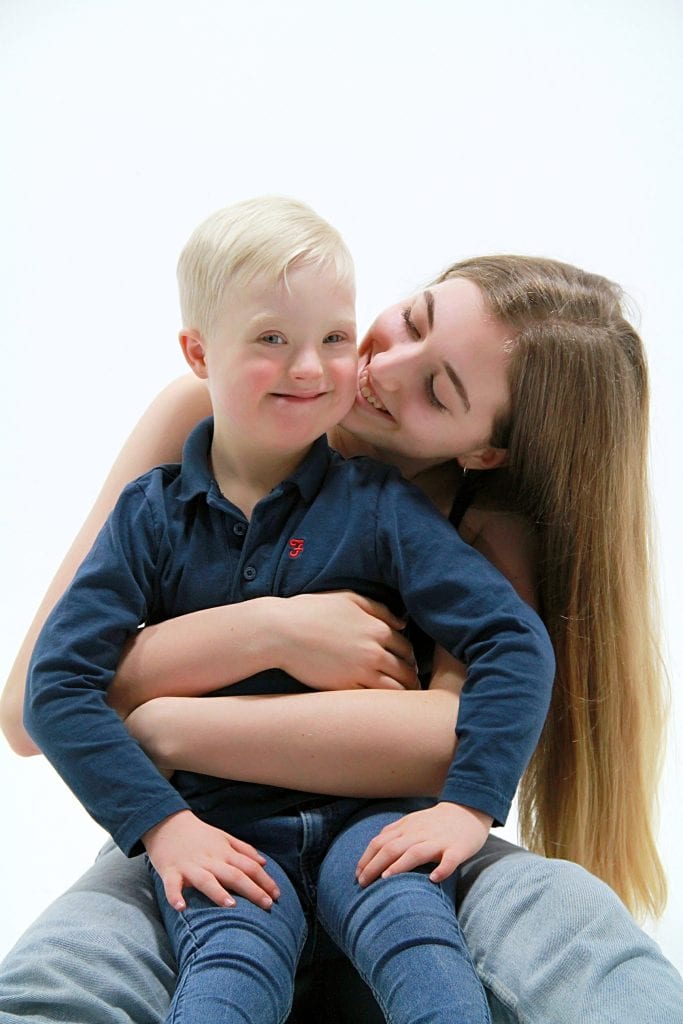 A teenage woman gives a boy who has Down's syndrome a hug