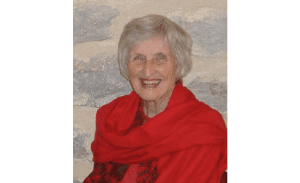 A portrait of Janet Carr. She is smiling broadly and wears a red scarf