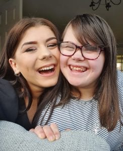 Two sisters hugging and smiling. One of them has Down's syndrome