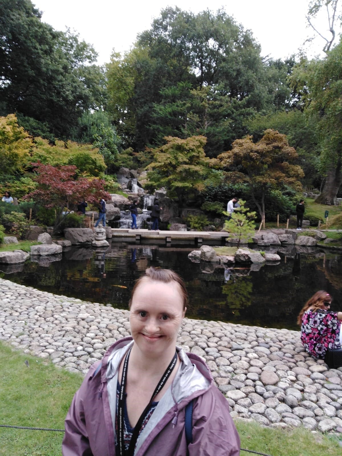 A woman who has Down's syndrome stands in front of a decorative garden pond