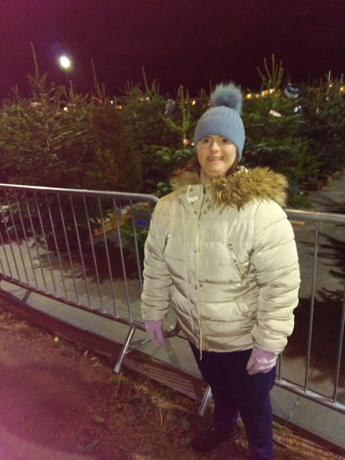 Kate stands in front of a lot of Christmas trees, well wrapped against the cold 