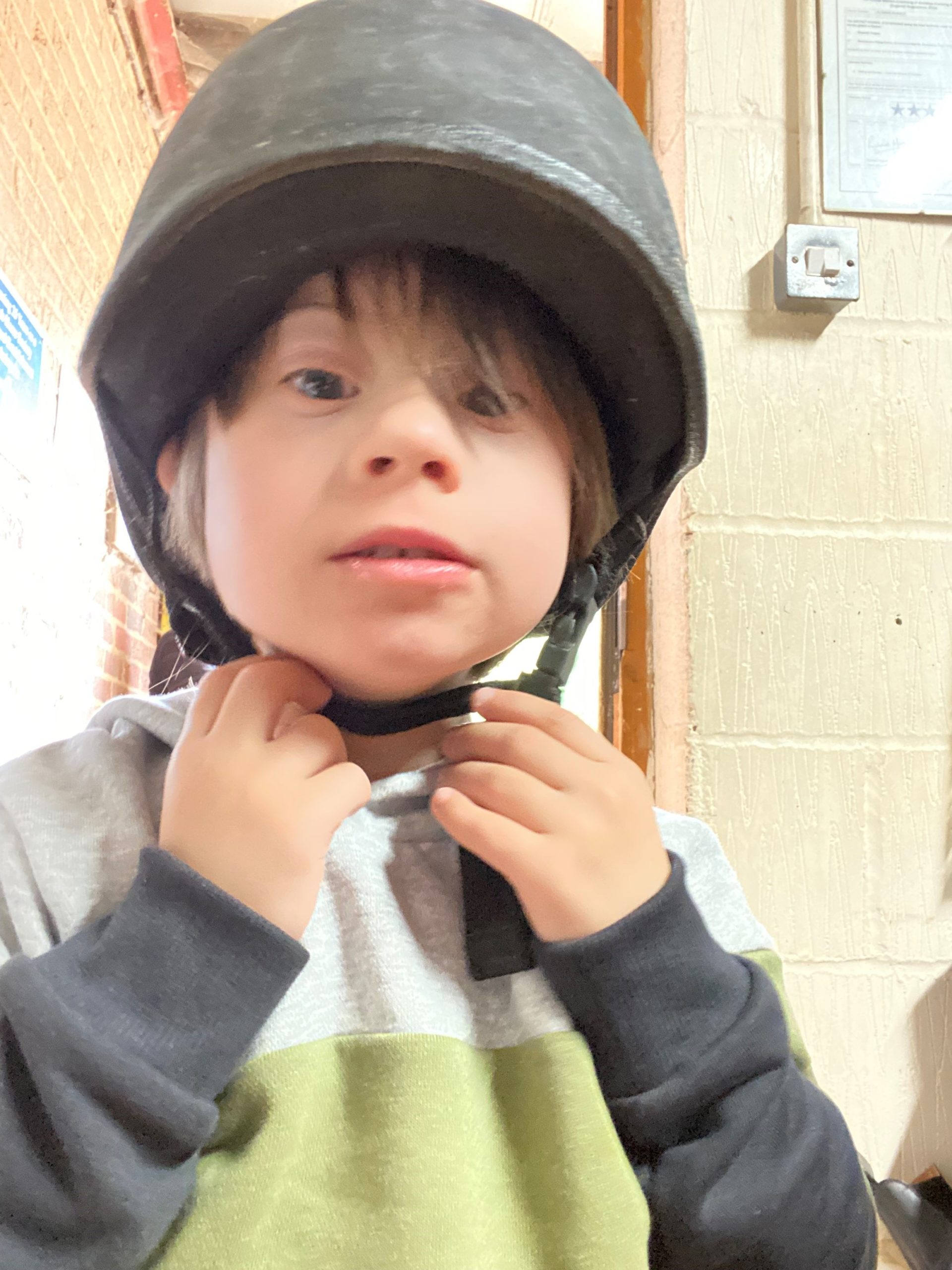 A young boy who has Down's syndrome wearing a riding hat