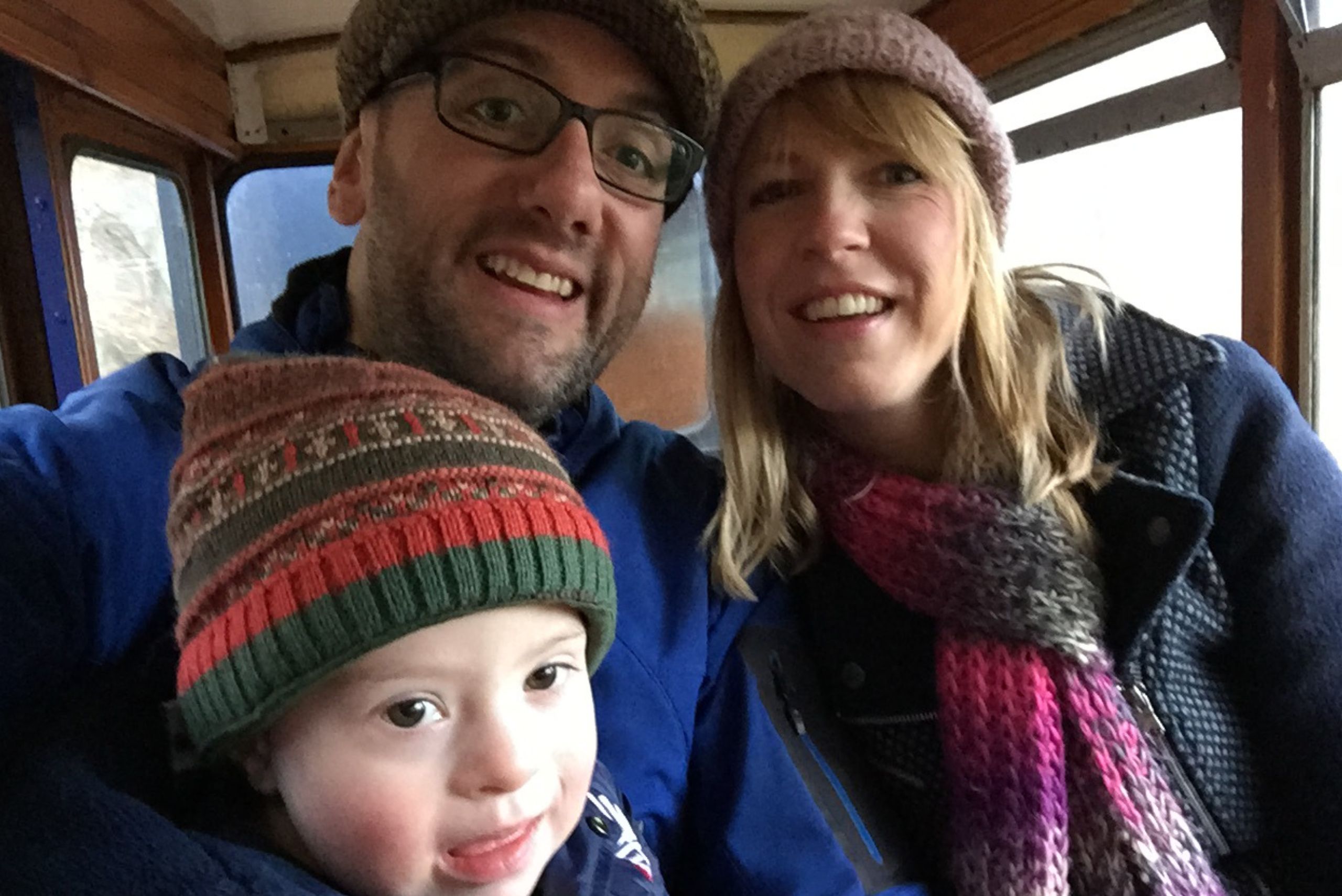 A well-wrapped up family, mum, dad and son (who has Down's syndrome) in a carriage.