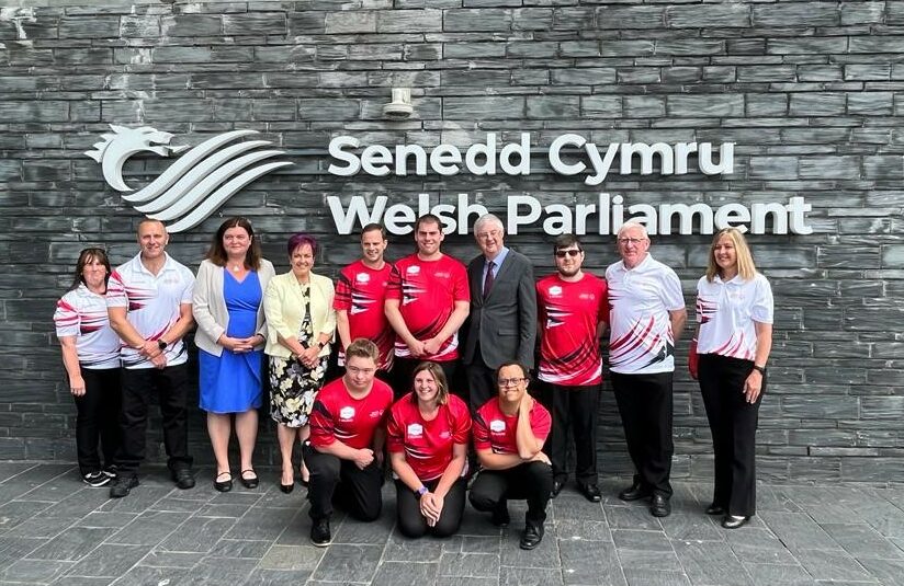 A group of athletes with learning disabilities pose outside the Senedd building in Cardiff in advance of competing in the Berlin Special Olympics World Games June 2023.