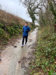 A young man who has Down's syndrome is running in a muddy lane