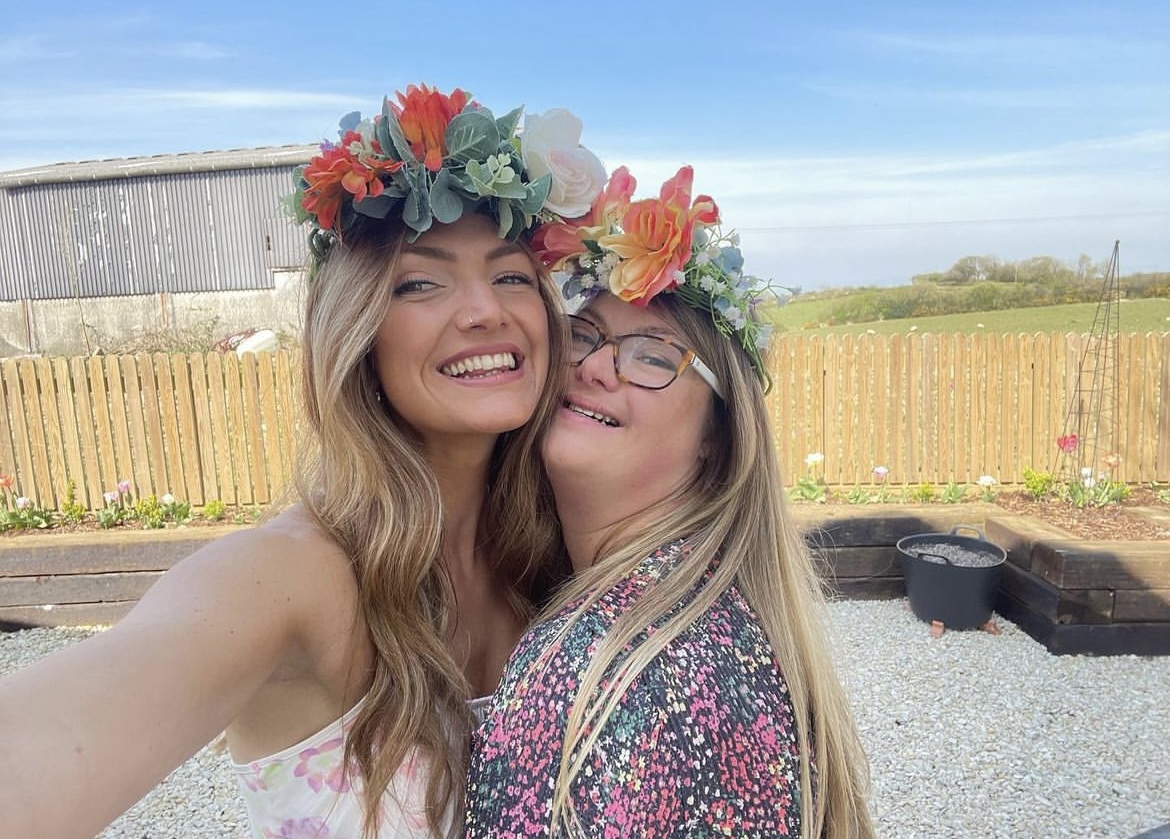 two girls laughing and hugging, wearing flowers in their hair